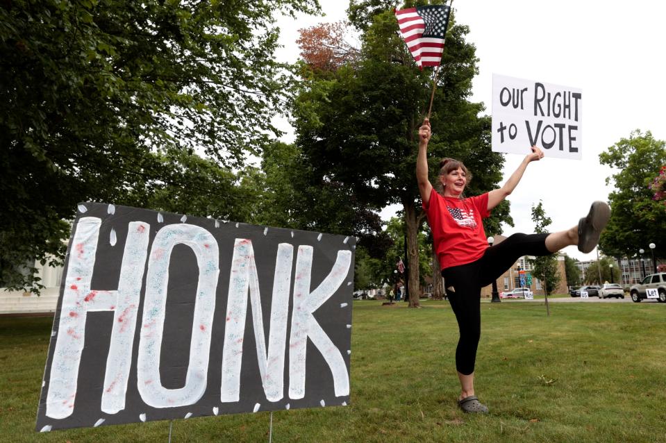 Holly Harnden of Marshall gets into the spirit of the protest, kicking with excitement as cars honk in support for her and other protesters at the Brooks Memorial Fountain in downtown Marshall on Wednesday, July 12, 2023. The protesters, who oppose the Ford electric vehicle battery plant planned for the area, generally show up on Wednesdays and Saturdays.