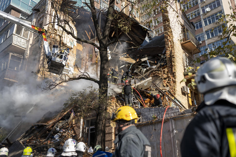 Firefighters work after a drone fired on buildings in Kyiv, Ukraine, Monday, Oct. 17, 2022. Waves of explosive-laden suicide drones struck Ukraine's capital as families were preparing to start their week early Monday, the blasts echoing across Kyiv, setting buildings ablaze and sending people scurrying to shelters. (AP Photo/Roman Hrytsyna)