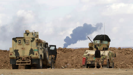 An Iraqi soldier looks on as smoke rises from oil wells in the Ajil field east of the city of Tikrit in the Salahuddin province, March 4, 2015. REUTERS/ Mahmoud Raouf