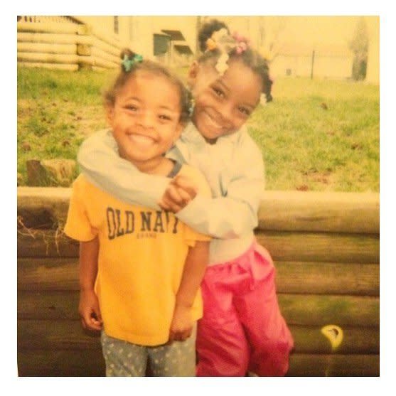 <strong>Hint:</strong> Don't be fooled by her small size. This tiny toddler, seen wrapping her arms around her younger sister, has now won 25 World Championship medals, which is the highest number of championship medals won by any gymnast, EVER.