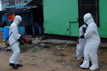 Health workers spray bleach solution on a woman suspected of having contracted the Ebola virus in Monrovia, Liberia, September 15, 2014. REUTERS/James Giahyue