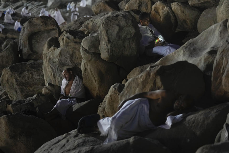 Peregrinos musulmanes toman una siesta en la colina rocosa conocida como la Montaña de la Misericordia, en la llanura de Arafat, durante el peregrinaje anual del hajj, el 8 de julio de 2022, cerca de la ciudad sagrada de La Meca, Arabia Saudí. (AP Foto/Amr Nabil)