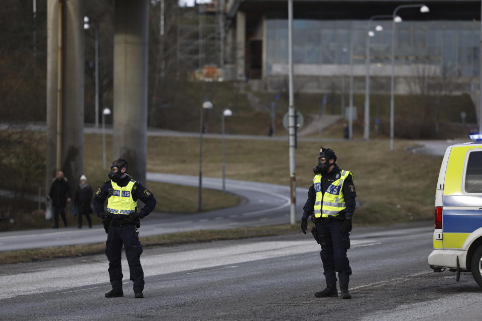 Police officers with gas masks stand guard near the Security Police's headquarters in Solna, north of Stockholm, Sweden, Friday Feb. 23, 2024. A suspected gas leak at the headquarters of Sweden’s security agency on Friday forced the authorities to evacuate some 500 people from the facility, Swedish broadcaster TV4 said. (Fredrik Persson/TT News Agency via AP)