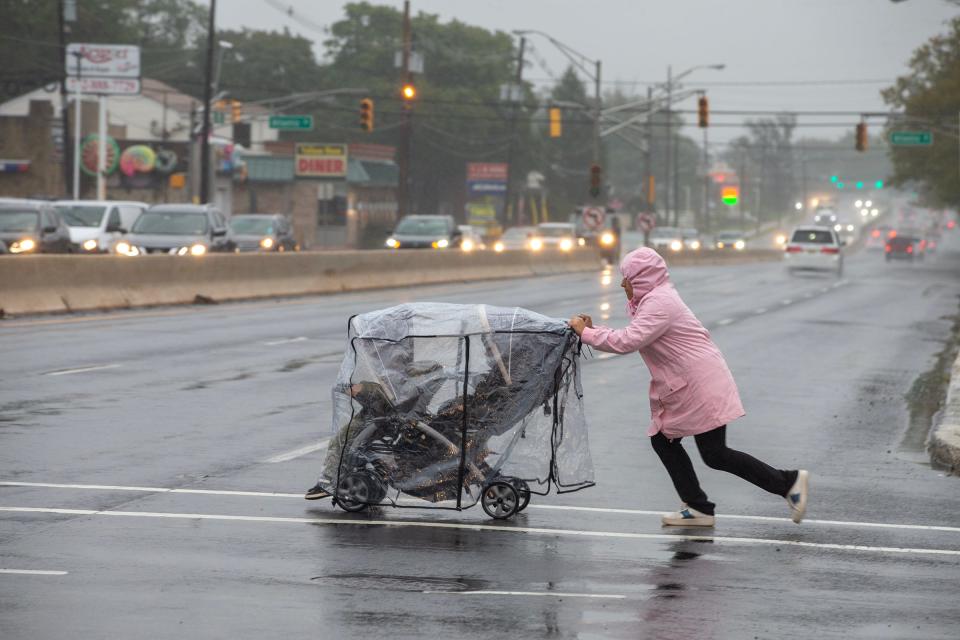 A woman pushes a stroller as she runs across Route 36 South in Keyport, NJ as remnants of Tropical Storm Ophelia continues to soak Monmouth County Monday, September 25, 2023.