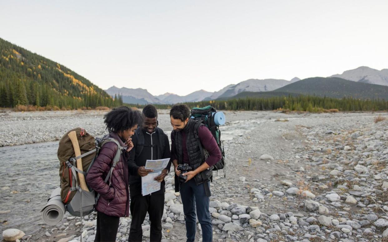 three people looking at map on hiking trail - best cities for hiking in the U.S.