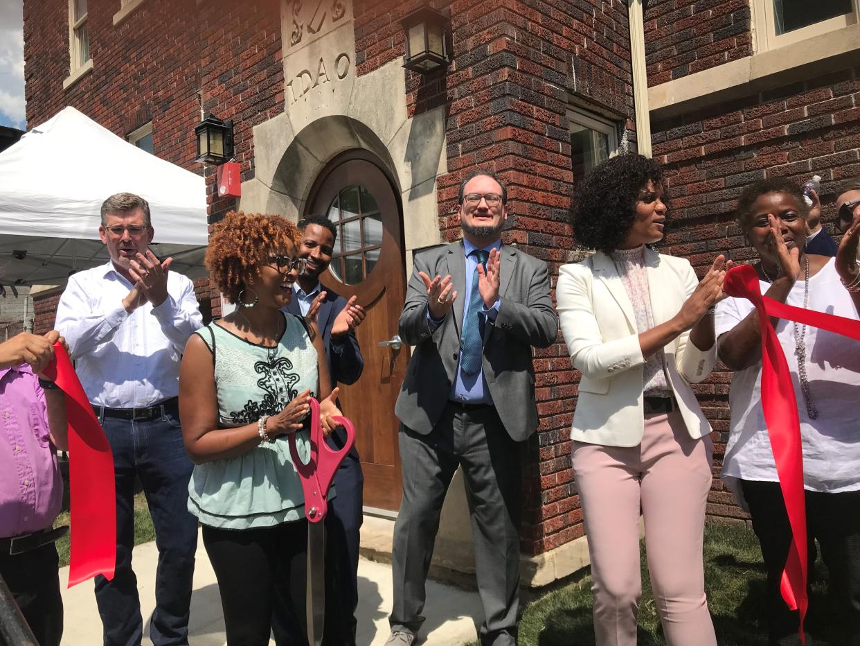 Amina Bell, operations director at EJ DevCo, the development company that oversaw renovation of a historic apartment building in Detroit, smiles Thursday after cutting the ribbon. In pink slacks to Bell's right is Detroit City Councilwoman Latisha Johnson. The initials "IDAO" over the doorway are thought to belong to the children of the builder, placed there in 1927. (Photo: Bill Laitner)