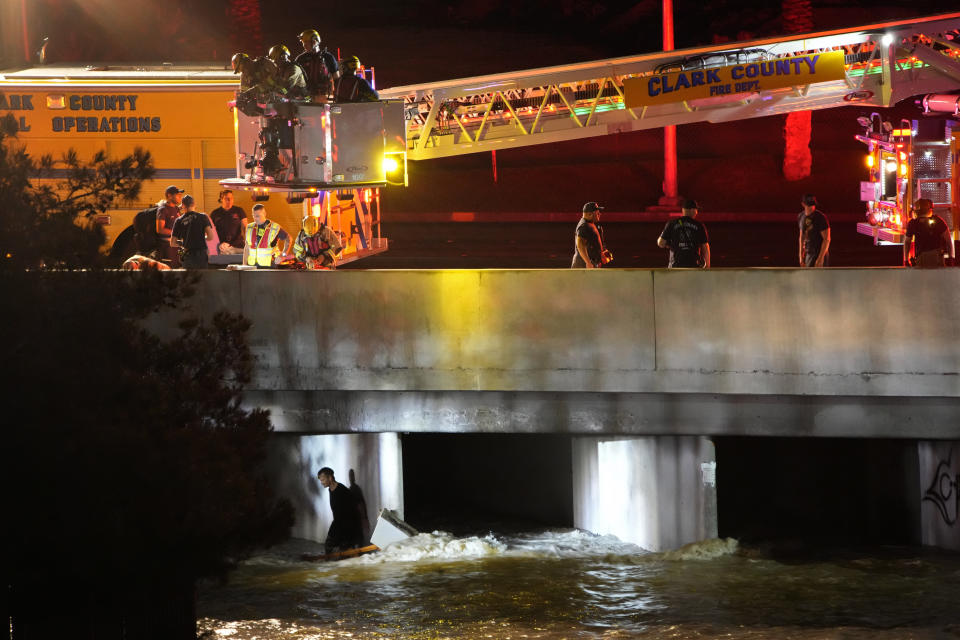 Clark County Fire Department officials attempt to rescue a man trapped in floodwaters in a flood channel Friday, Sept. 1, 2023, in Las Vegas. (AP Photo/John Locher)