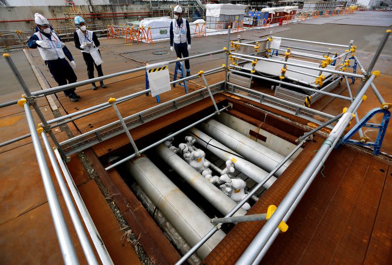 TEPCO employees are seen next to the part of an underground ice wall unit at tsunami-crippled Fukushima Daiichi nuclear power plant in Okuma town, Fukushima prefecture