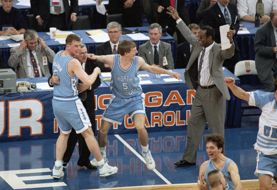 FILE - In this April 5, 1993, file photo, North Carolina coach Dean Smith is hugged by Pat Sullivan, left, as Henrik Rodl (5) and assistant coach Randy Weil, right, celebrate the team's 77-71 win over Michigan for the NCAA men's basketball championship in New Orleans. Rodl, now the coach of the German team, says it’s an honor to coach in the Olympics, just as Smith did in 1976. (AP Photo/Bill Haber, File)