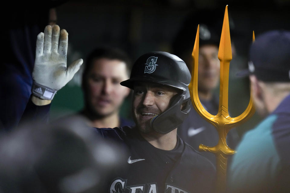 Seattle Mariners' AJ Pollock, center, celebrates with teammates in the dugout after hitting a solo home run against the Oakland Athletics during the eighth inning of a baseball game in Oakland, Calif., Tuesday, May 2, 2023. (AP Photo/Godofredo A. Vásquez)