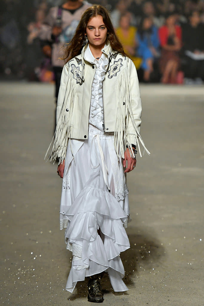 <p>A model walks the Coach Spring 2019 show during New York Fashion Week wearing a white leather fringe jacket over a white ruffle blouse and skirt. (Photo: Getty Images) </p>