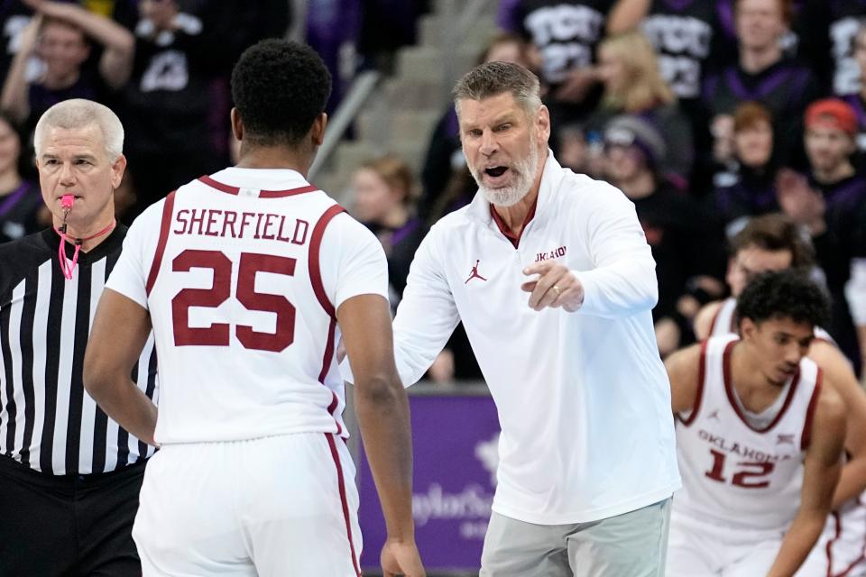 OU coach Porter Moser, right, talks to Grant Sherfield (25) as he walks off the court in the first half of a 79-52 loss at No. 11 TCU on Tuesday night in Fort Worth, Texas.