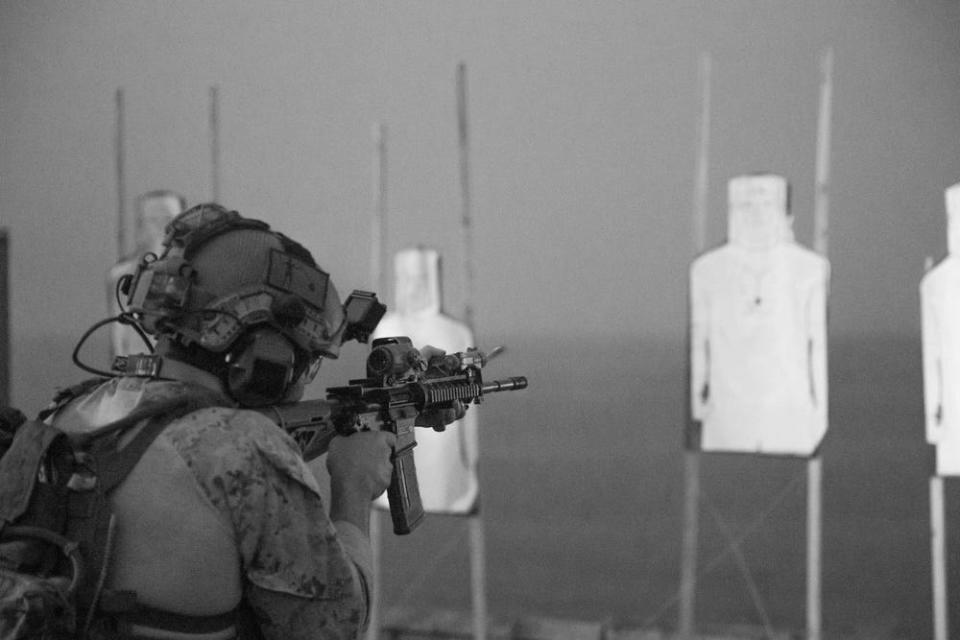 a marine fires a carbine rifle at a target