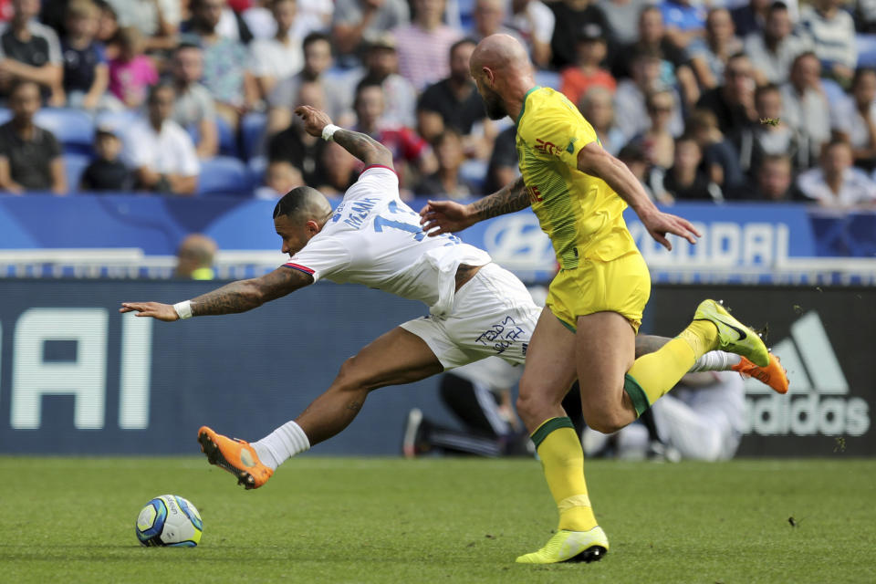 Lyon's Memphis Depay, left, challenges for the ball with Nantes' Nicolas Pallois, right, during the French League 1 soccer match between Lyon and Nantes, at the Stade de Lyon in Decines, outside Lyon, France, Saturday, Sept. 28, 2019. (AP Photo/Laurent Cipriani)