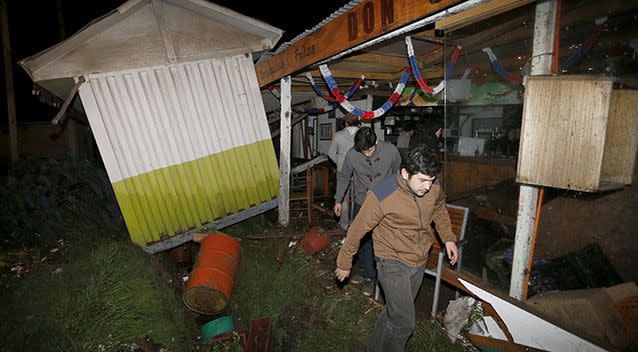 People recover items from a destroyed shop caused by the waves in Concon city, Chile. Photo: Reuters