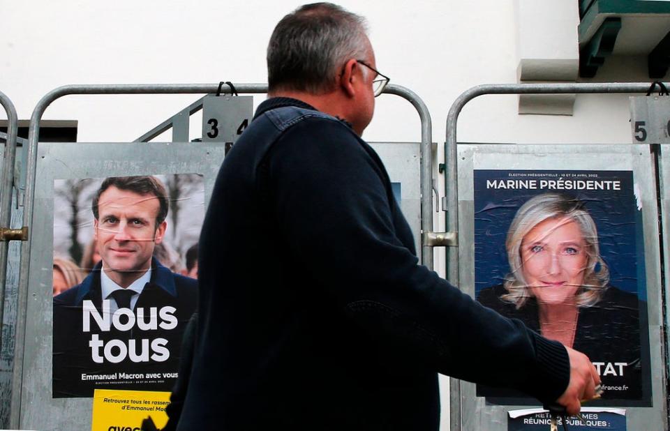 A man walks past presidential campaign posters of Macron and Le Pen in Anglet, southwestern France, 8 April 2022 (AP)