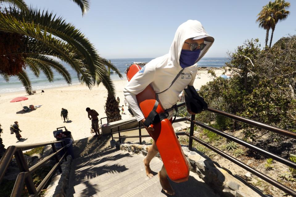 A lifeguard wearing a face covering heads up the steps in Heisler Park in Laguna Beach.