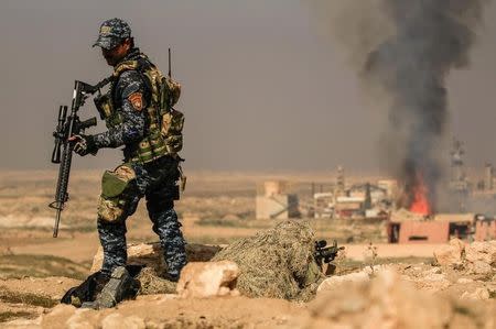 Smoke rises from sugar factory as Iraqi security forces sniper aims his weapon toward Mosul's airport during a battle with islamic state's militants south west Mosul, Iraq February 23, 2017. REUTERS/Zohra Bensemra