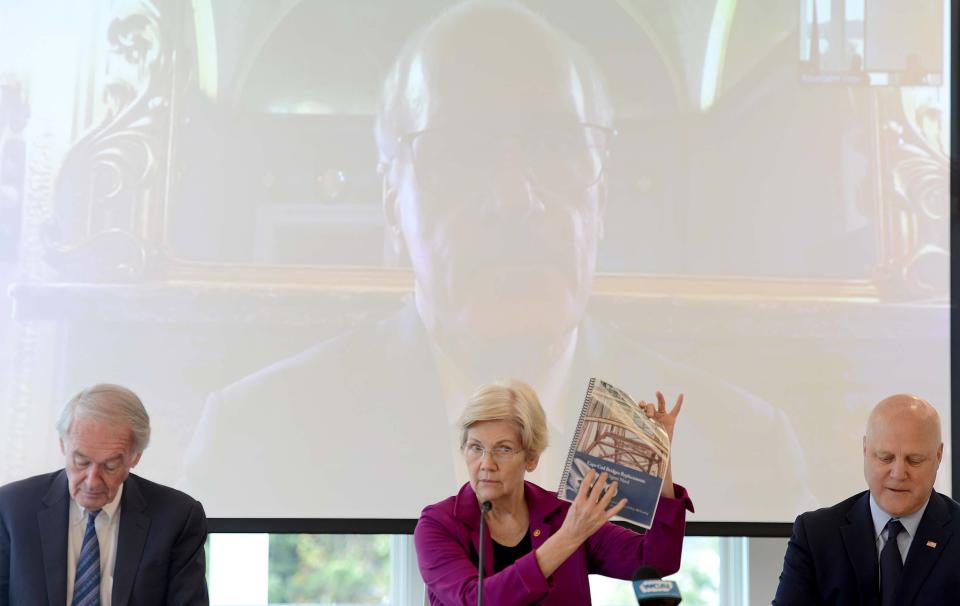 Sen. Elizabeth Warren, holds up a copy of a bridge construction report as she is joined by Sen. Ed Markey, left, and Mitch Landrieu at Massachusetts Maritime Academy which hosted a meeting Friday of federal, state and local officials to talk about construction of the new canal bridges. Landrieu is a special adviser to President Biden.