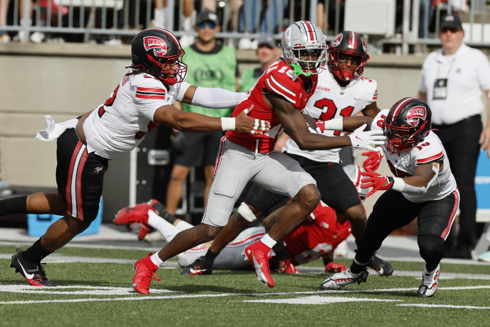 Ohio State receiver Marvin Harrison, center, tries to run past Western Kentucky defensive lineman Marcus Patterson, left, and linebacker Desmyn Baker during the first half of an NCAA college football game, Saturday, Sept. 16, 2023, in Columbus, Ohio. (AP Photo/Jay LaPrete)