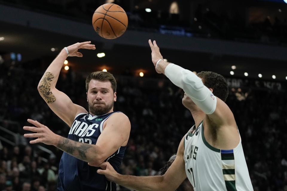 Dallas Mavericks' Luka Doncic passes around Milwaukee Bucks' Brook Lopez during the first half of an NBA basketball game Sunday, Nov. 27, 2022, in Milwaukee. (AP Photo/Morry Gash)