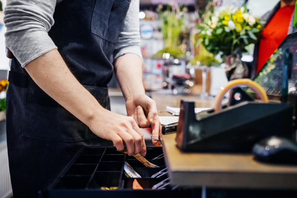 A florist putting some cash in his register after a sale to a customer.