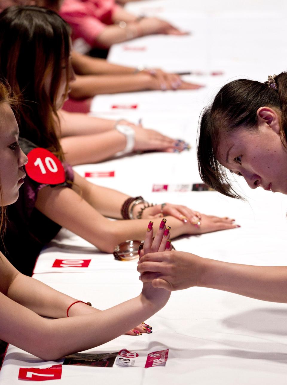 A judge checks on the contestants' nails during a nail art creative design contest at the China 2011 Hair and Beauty exhibition in Beijing, China.