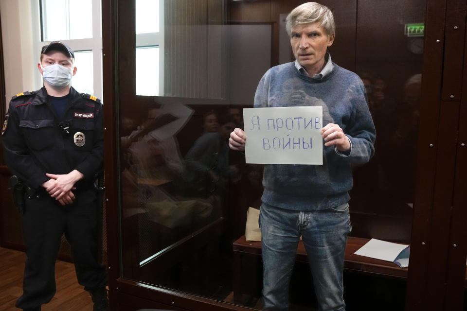 FILE - Alexei Gorinov holds a sign reading, "I am against the war," while standing in a defendants’ cage in a courtroom in Moscow, Russia, on June 21, 2022. Gorinov is serving seven years for speaking out against Russia sending troops to Ukraine. His supporters say he suffers from a respiratory condition and his health has deteriorated during six weeks in solitary confinement. (AP Photo, File)