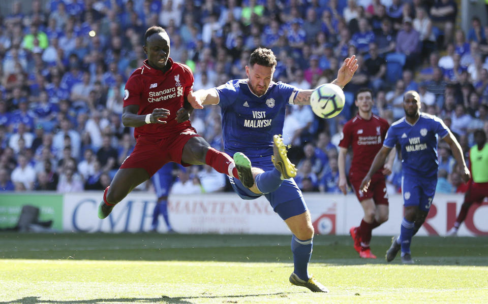 Liverpool's Sadio Mane and Cardiff City's Sean Morrison, right, battle for the ball during the English Premier League soccer match at The Cardiff City Stadium, Cardiff, Wales, Sunday April 21, 2019. (David Davies/PA via AP)