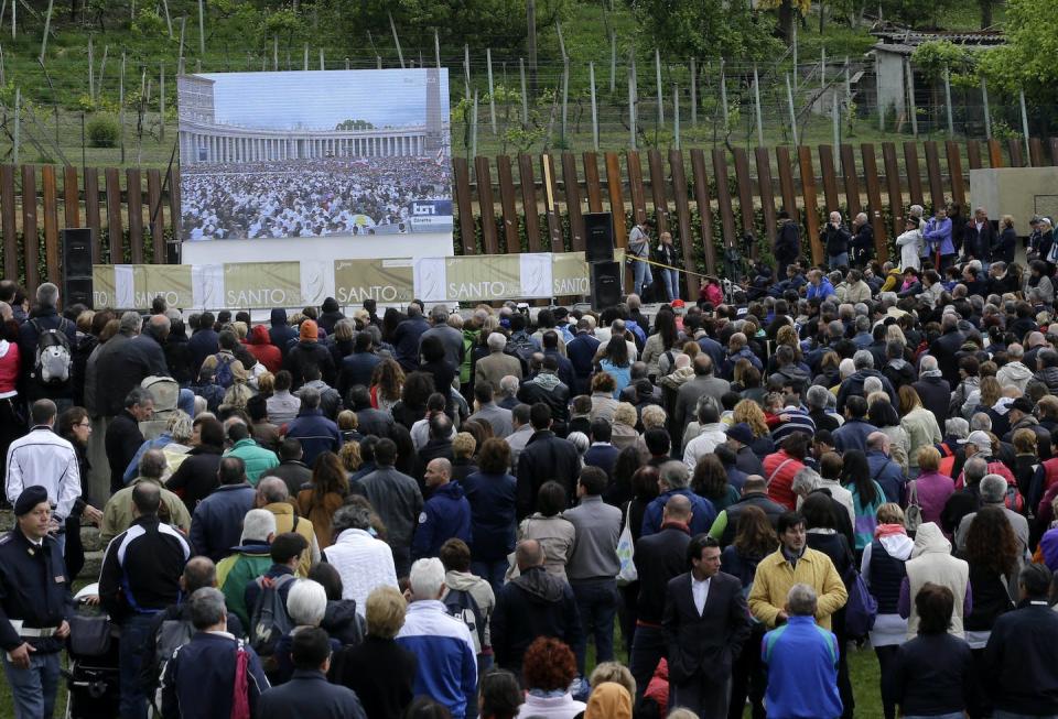 People watch the screening of the canonization of Pope John XXIII and Pope John Paul II broadcast from the Vatican in 2014. <a href="https://newsroom.ap.org/detail/ItalyVaticanPopesSaints/30d689f0aa09477d90a4da0a65849824/photo?Query=John%20Paul%20II%20saint&mediaType=photo&sortBy=&dateRange=Anytime&totalCount=747&currentItemNo=36" rel="nofollow noopener" target="_blank" data-ylk="slk:AP Photo/Luca Bruno;elm:context_link;itc:0;sec:content-canvas" class="link ">AP Photo/Luca Bruno</a>