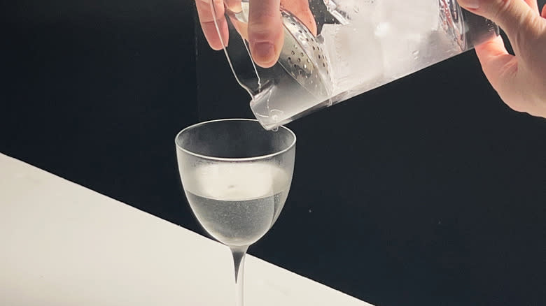 straining martini into glass