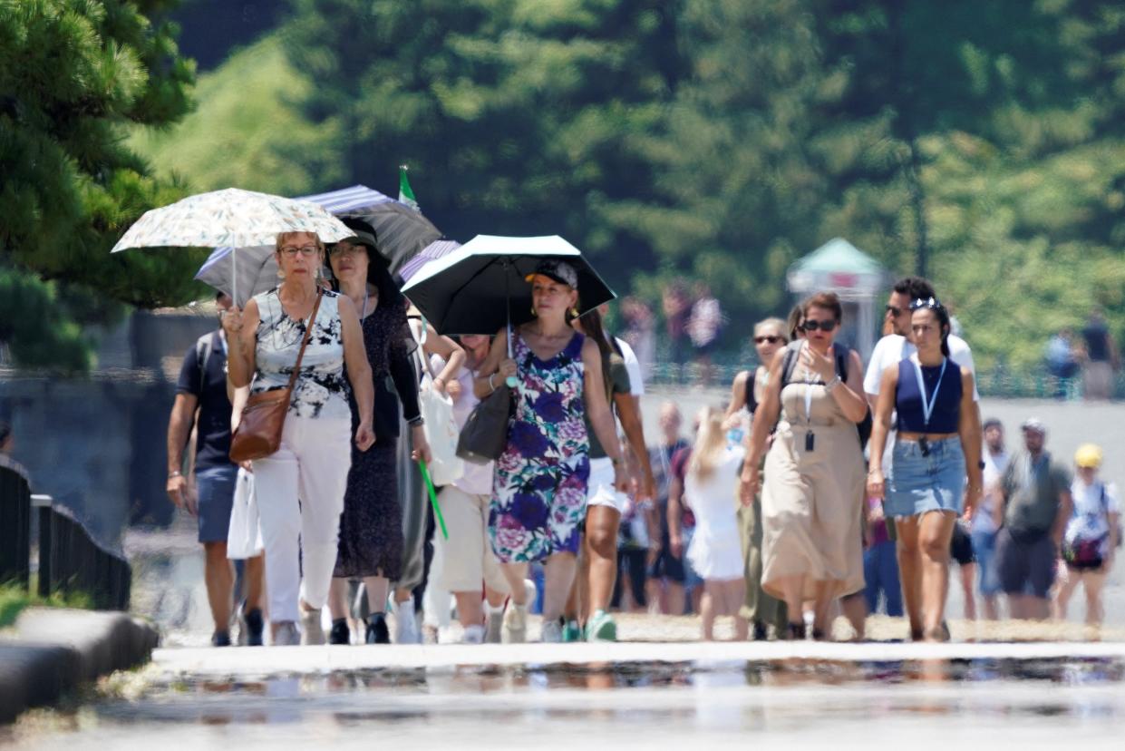 Foreign tourists walk on the pavement along the Imperial Palace Gardens in the intense heat in Tokyo (AFP/Getty)