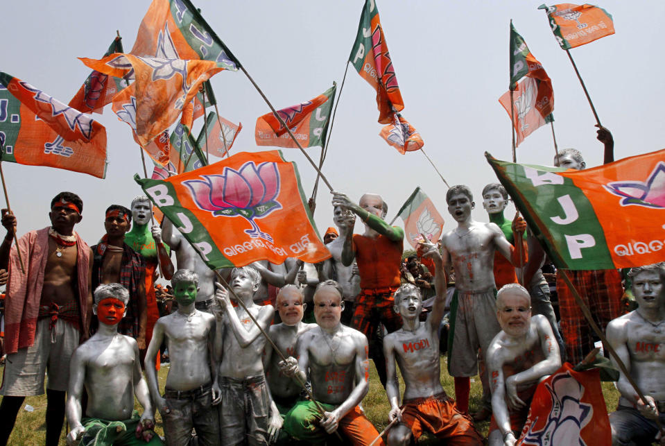 Supporters of the main opposition Bharatiya Janata Party, bodies painted, wave the party flag to welcome prime ministerial candidate Narendra Modi for an election campaign in Balasore, about 200 kilometers (125 miles) from Bhubaneswar, India, Friday, April 11, 2014. The multiphase voting across the country runs until May 12, with results for the 543-seat lower house of Parliament announced May 16. (AP Photo/Biswaranjan Rout)
