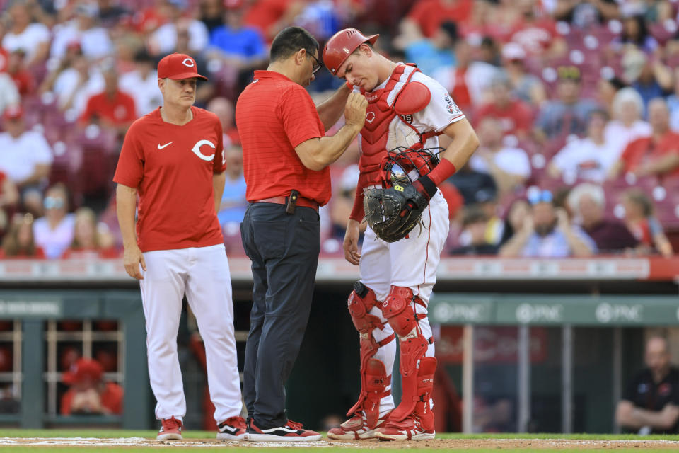 Cincinnati Reds' Tyler Stephenson, right, is checked by assistant athletic trainer Tomas Vera during the first inning of the team's baseball game against the St. Louis Cardinals in Cincinnati, Friday, July 22, 2022. (AP Photo/Aaron Doster)