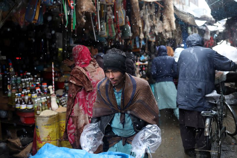 Afghan men walk in a market area during a snowfall in Kabul
