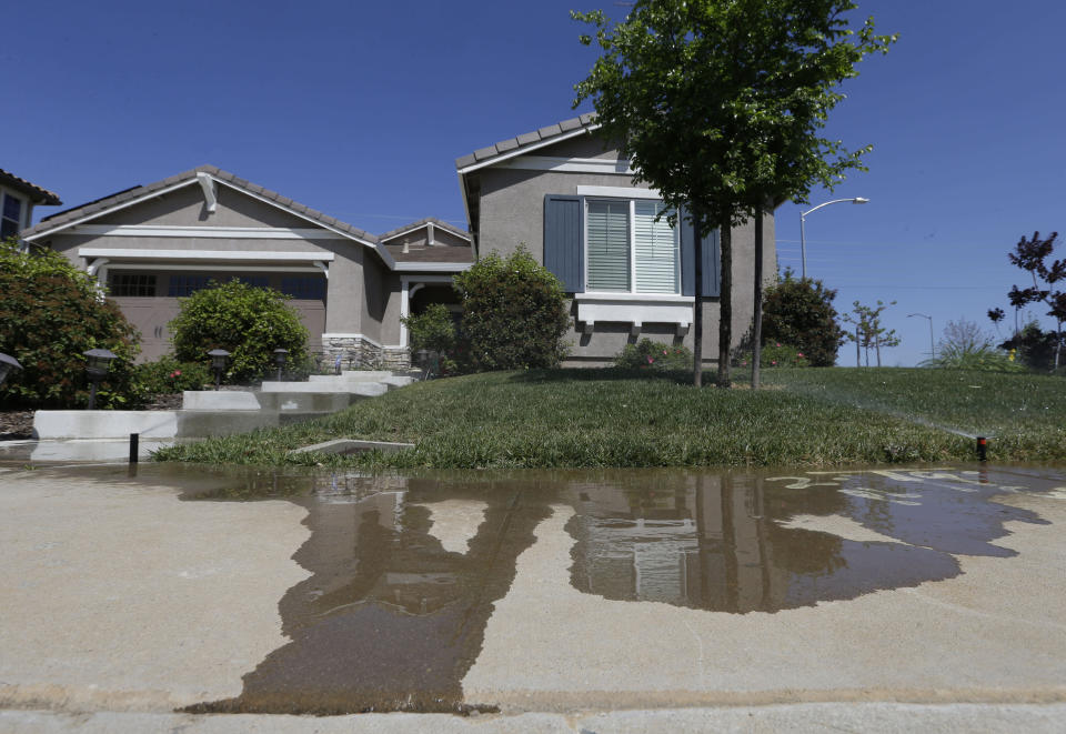 FILE — Water flows down a sidewalk from water sprinklers running at a home Thursday, April 2, 2015, in Rancho Cordova, Calif. The State Water Resources Control Board voted Tuesday, Jan. 4, 2022 to adopt mandatory water use restrictions that prohibit excessive runoff from sprinklers. (AP Photo/Rich Pedroncelli, File)