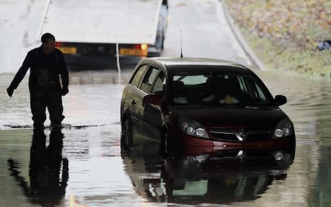 A car stuck in flood water under a bridge in Galgate, Lancashire - Credit: Peter Byrne/PA