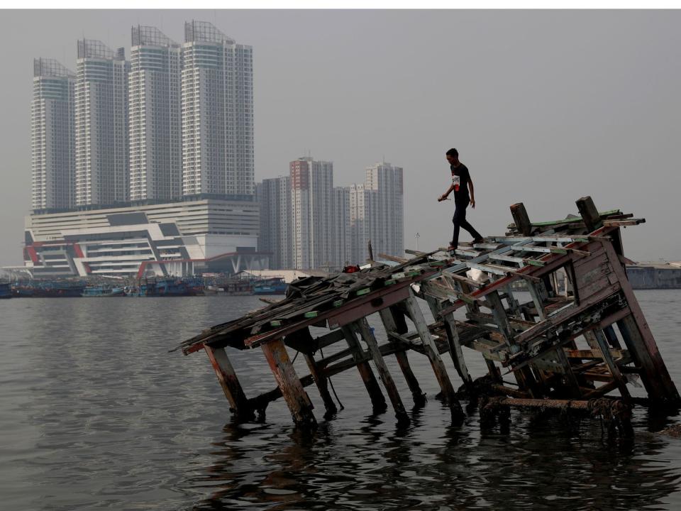 Pollution coronavirus A combination picture shows a man walking on top of the wreckage of a wooden boat, as smog covers the sky, July 26, 2018, (top) and a view of the same location pictured during the coronavirus disease (COVID-19) outbreak, in North Jakarta, Indonesia