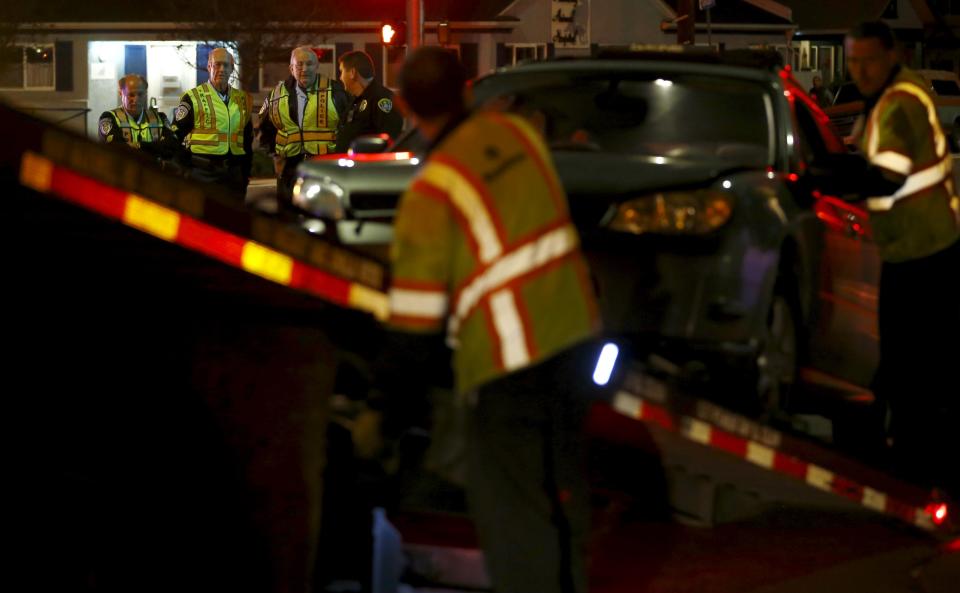 Retired Senior Volunteer Patrol members, top left from L-R, Steve Rubin, Henry Miller and Robert Stewart talk with a San Diego Police officer as a vehicle is towed away from an accident scene in San Diego, California, United States February 10, 2015. (REUTERS/Mike Blake)