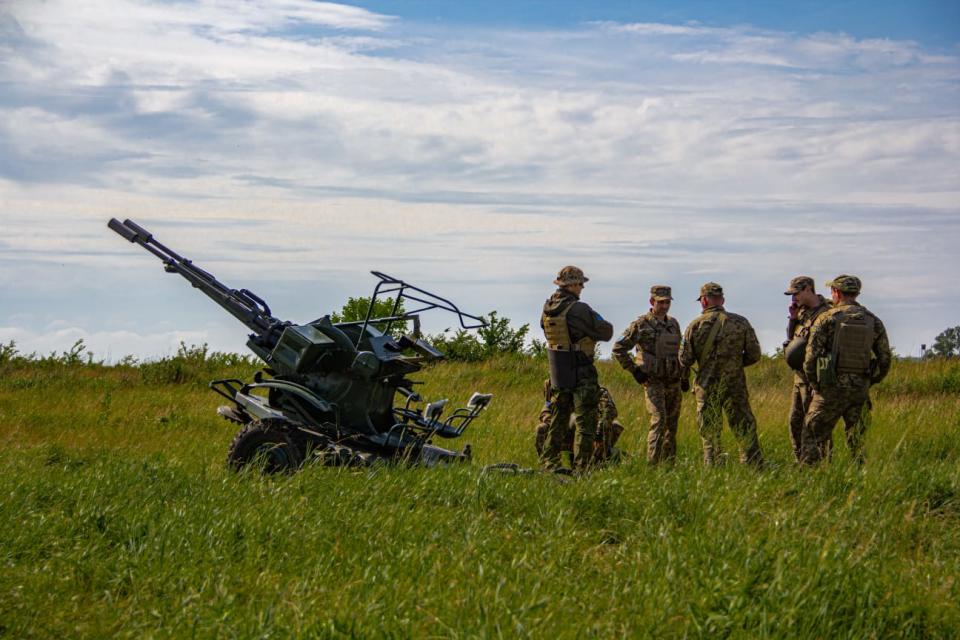 Ukrainian soldiers with the 32nd Separate Mechanized Brigade gather next to an anti-aircraft autocannon in May. (Oleksandr Bordian / Courtesy)