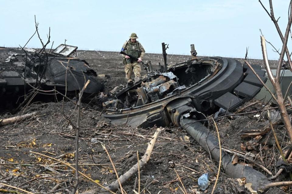 A Ukrainian soldier stands next to the wreckage of a burnt Russian tank outside of the village of Mala Rogan, east of Kharkiv, on April 1, 2022.