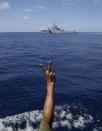 A Philippine Marine gestures at a Chinese Coast Guard vessel which tries to block a Philippine Government vessel AM700 from approaching the Second Thomas Shoal, locally known as Ayungin Shoal, to resupply and replace fellow marines who were deployed for almost five months Saturday, March 29, 2014 off South China Sea on the West Philippine Sea. (AP Photo/Bullit Marquez)