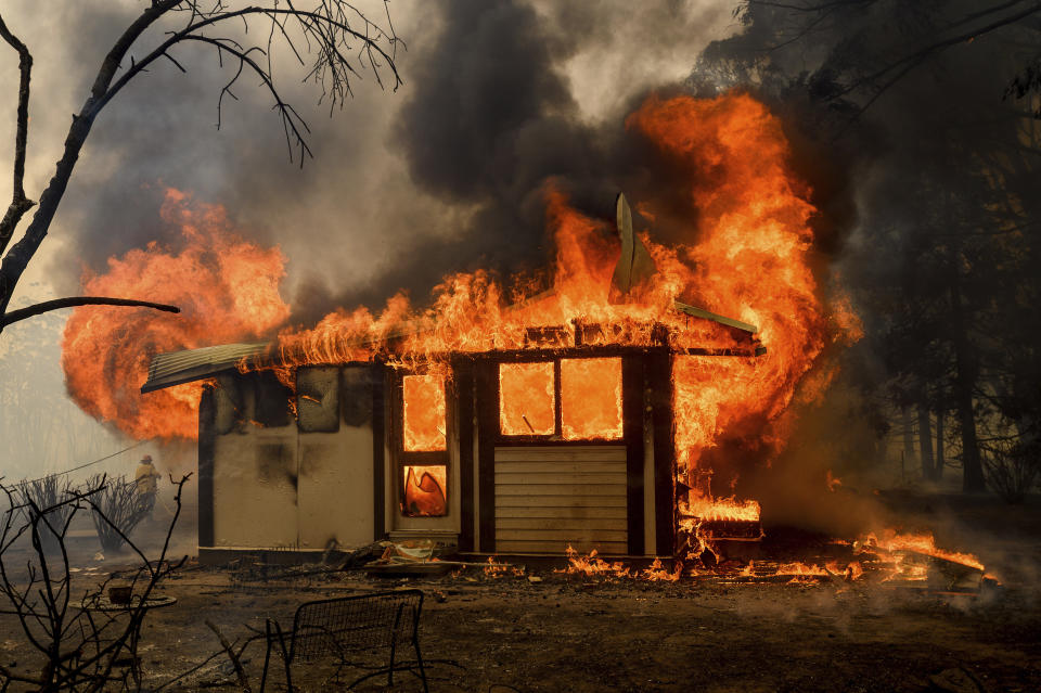 FILE - In this Jan. 23, 2020, file photo, flames from the Morton Fire consume a home near Bundanoon, Australia. Australia has sweltered through its fourth-hottest year on record despite the usually cooling impact in recent months of the La Nina climate pattern, the nation’s weather bureau said on Friday, Jan. 8, 2021. (AP Photo/Noah Berger, File)