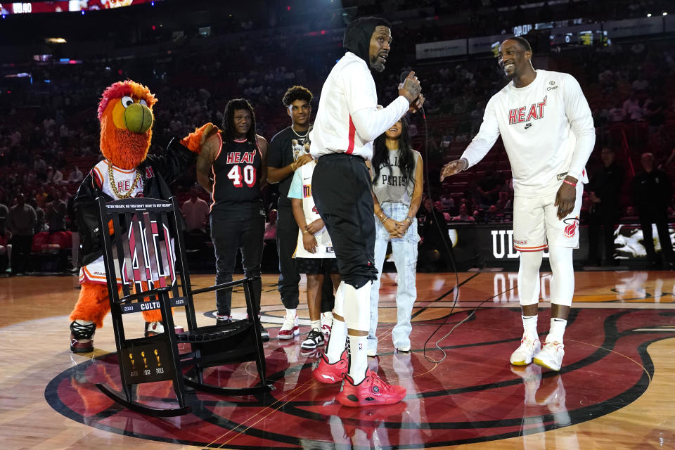 Miami Heat forward Udonis Haslem, left, stands with center Bam Adebayo, right, as he is presented with a rocking chair during a ceremony before an NBA basketball game against the Orlando Magic, Sunday, April 9, 2023, in Miami. Haslem's final regular-season game with the Heat is Sunday. (AP Photo/Lynne Sladky)