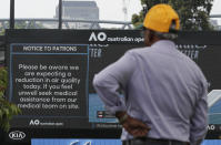 A spectator reads a sign warning of air quality ahead of the Australian Open tennis championship in Melbourne, Australia, Saturday, Jan. 18, 2020. (AP Photo/Lee Jin-man)