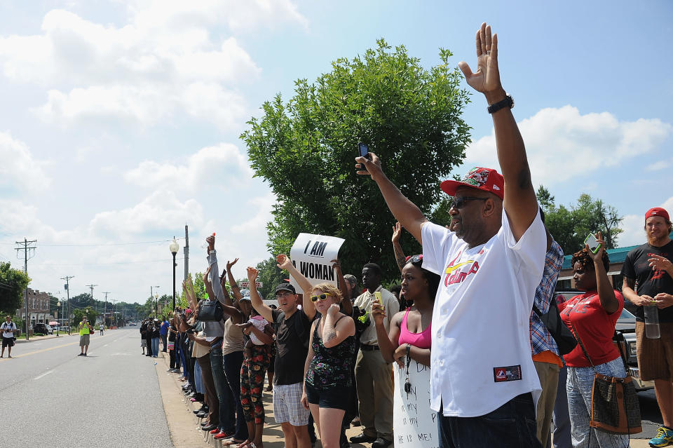 FERGUSON, MO - AUGUST 11:  Protestors stand with arms in the air during a protest of the shooting death of 18-year-old Michael Brown by a Ferguson police officer, outside Ferguson Police Department Headquarters August 11, 2014 in Ferguson, Missouri.  Civil unrest broke out as a result of the shooting of the unarmed black man as crowds looted and burned stores, vandalized vehicles and taunted police officers. Dozens were arrested for various infractions including assault, burglary and theft.  (Photo by Michael B. Thomas/Getty Images)