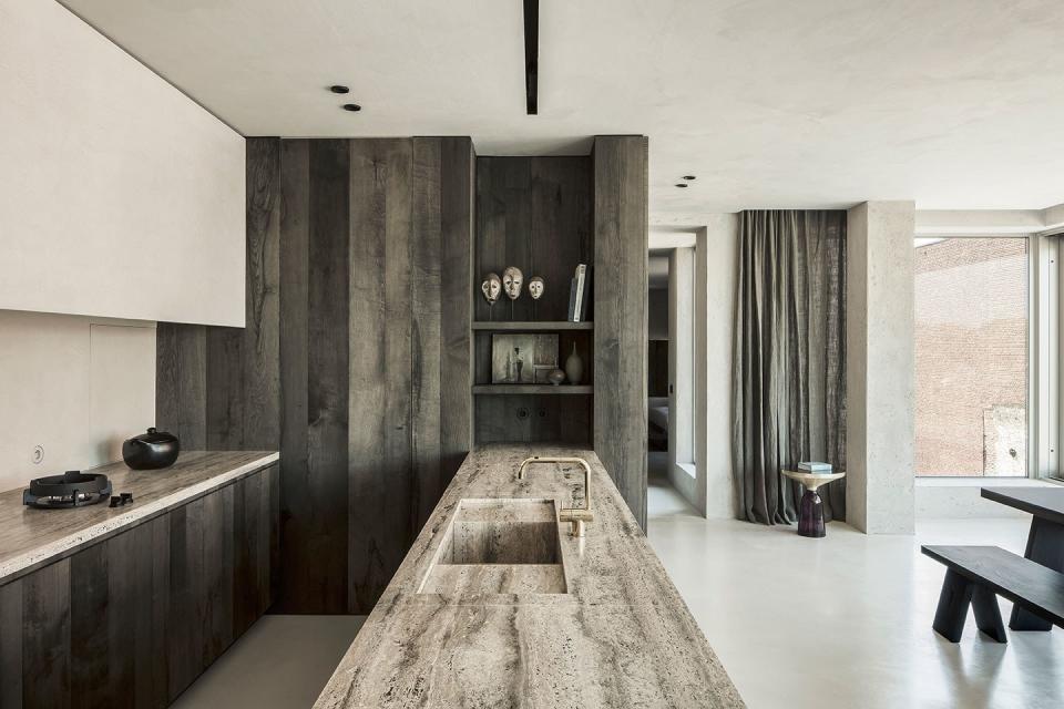This elegant monochromatic kitchen by Arjaan De Feyter belongs to an apartment inside the Axel Vervoordt Kanaal complex comprising old silos in Wijnegem, Belgium. The travertine grigio slabs provide a contrasting texture to the concrete, tinted ash wood, and mineral plaster walls found elsewhere in the home.