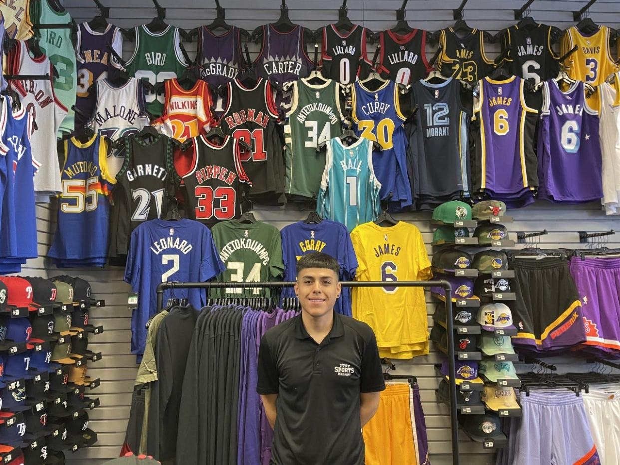 Daniel Murillo stands in front of the basketball jersey wall at Just Sports in downtown Phoenix