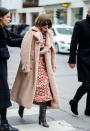 <p>Bei der Mailand Fashion Week angekommen, kamen der flauschige Coat und die Lieblingsstiefel erneut zum Einsatz. Allerdings peppte Anna Wintour das Outfit diesmal mit einem wadenlangen Kleid mit wildem Seventies-Print auf. Wadenlanges Kleid und kniehohe Stiefel – Wintour zeigt gleich mit mehreren Outfits, wie gut das funktioniert. (Bild: Getty Images) </p>