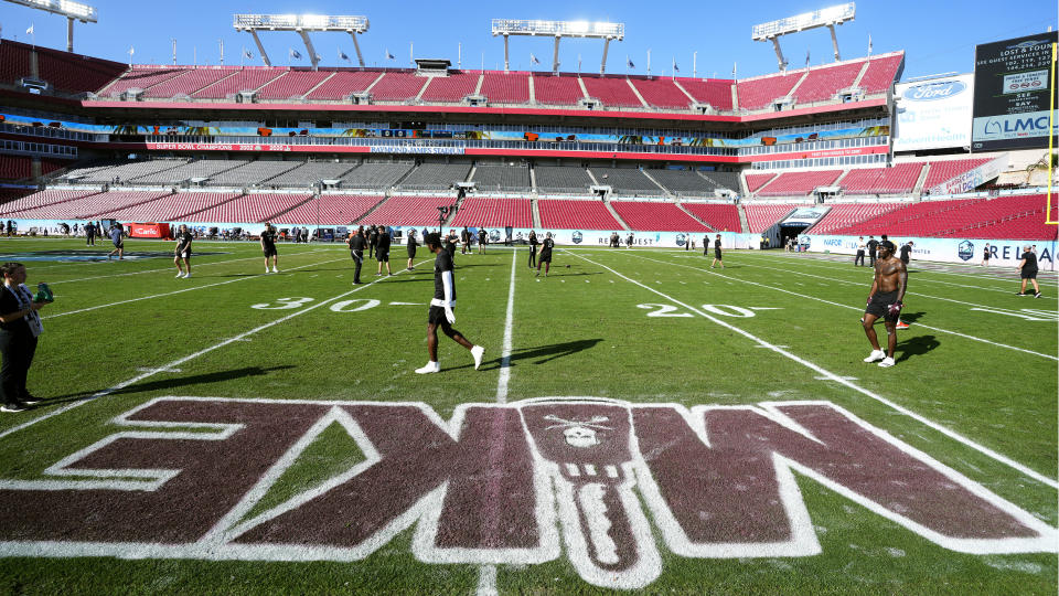 Mississippi State players warm up near a painting of "Mike" on the field before the ReliaQuest Bowl NCAA college football game against Illinois Monday, Jan. 2, 2023, in Tampa, Fla. The painting is in honor of their former head coach Mike Leach, who died Dec. 13, 2022, from a heart condition. (AP Photo/Chris O'Meara)